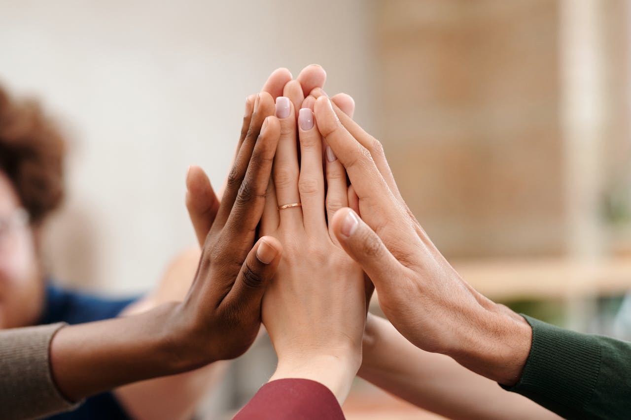 embark Close-up of diverse group hands high-fiving symbolizing teamwork and unity.